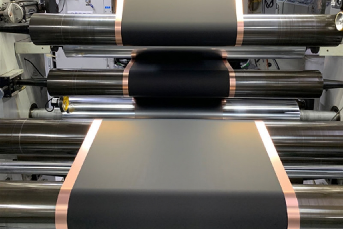 Rollers processing a dark sheet with metallic edge strips